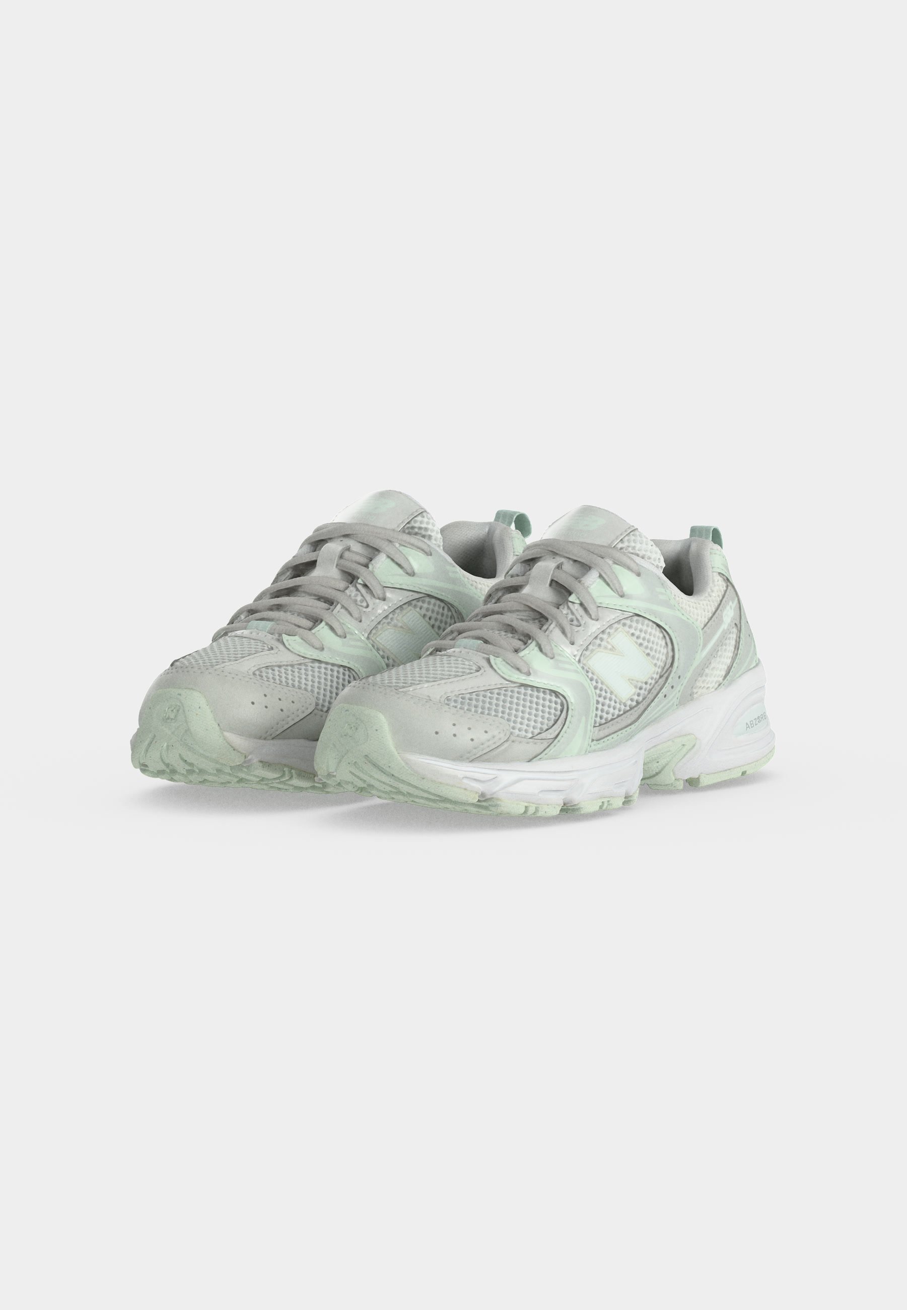Par de zapatillas deportivas gris claro y verde menta con parte superior de malla y material sintético y suelas texturizadas sobre fondo blanco.