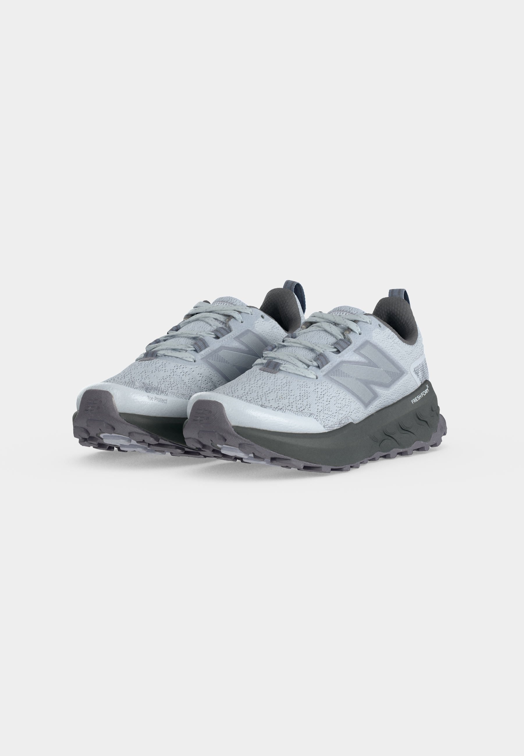 Zapatillas deportivas de color gris claro con textura de tejido, suelas gruesas de color gris oscuro, cordones y logo de la marca en los laterales, mostradas desde un ángulo frontal de tres cuartos.