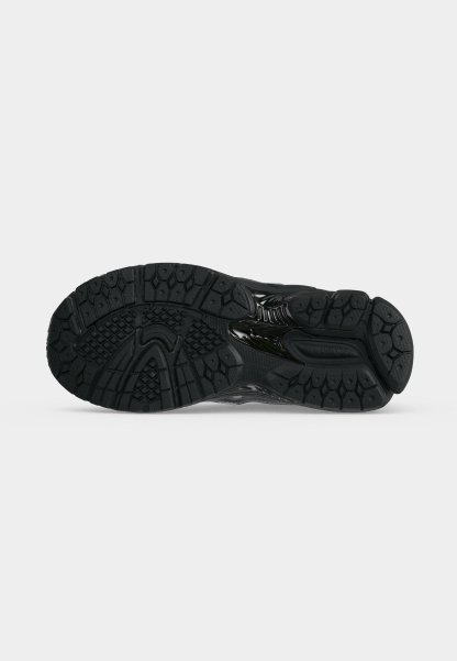 Suela negra de zapato deportivo con patrones texturizados para mejor agarre, mostrada desde abajo sobre un fondo blanco liso.