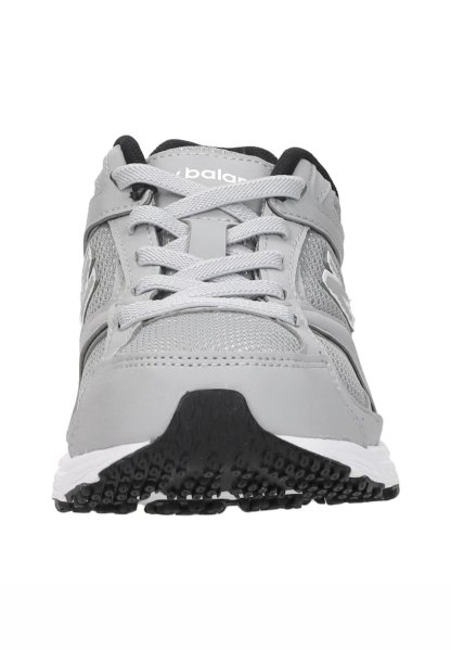 Zapatilla deportiva gris y negra con parte superior de malla y cuero, cordones blancos y suela negra texturizada vista desde el frente.