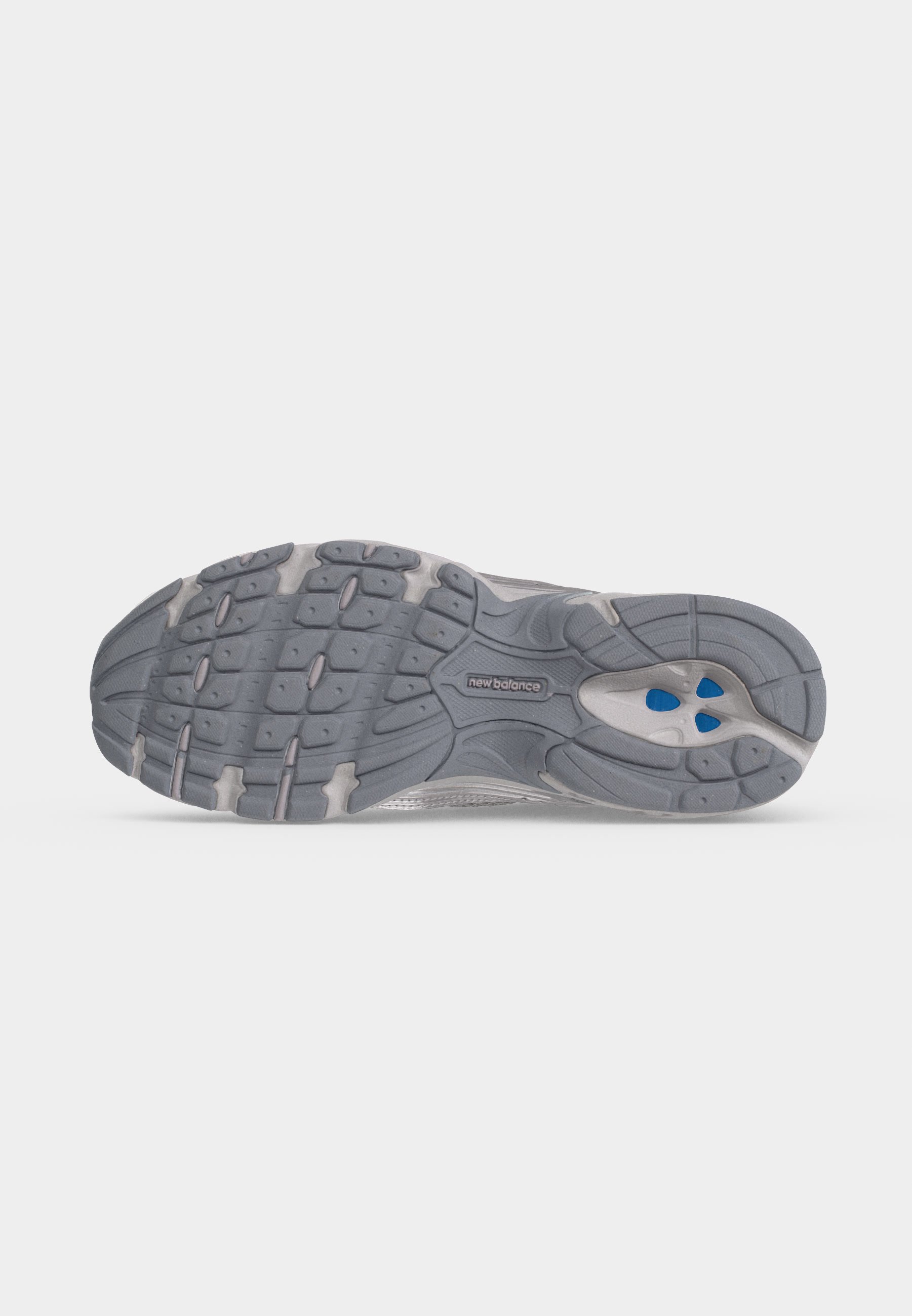 Suela de una zapatilla de correr New Balance gris con banda de rodadura texturizada y acentos azules en la zona del talón.