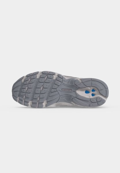 Suela de una zapatilla de correr New Balance gris con banda de rodadura texturizada y acentos azules en la zona del talón.