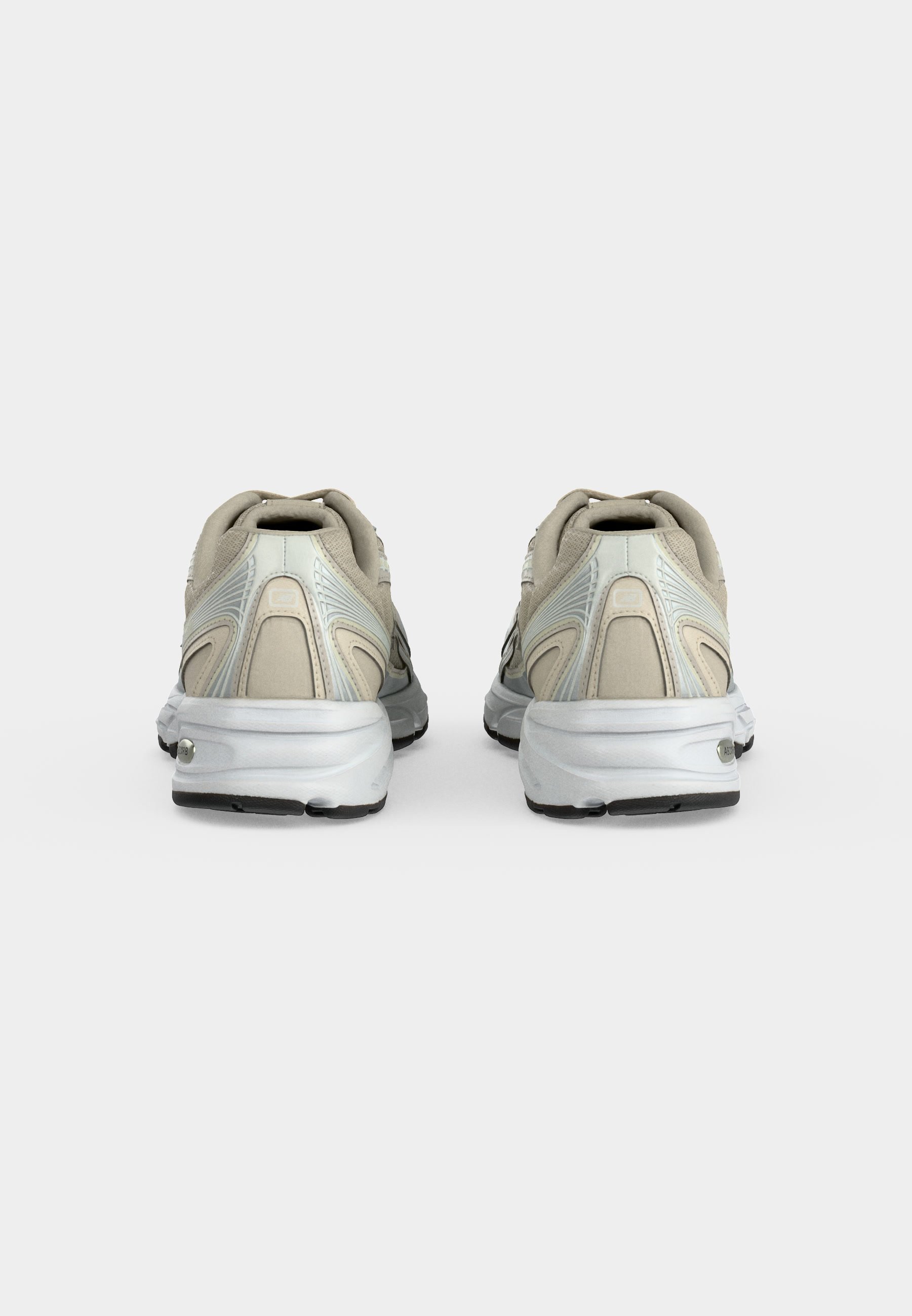 Par de zapatillas deportivas beige y blancas vistas por detrás sobre un fondo liso gris claro.