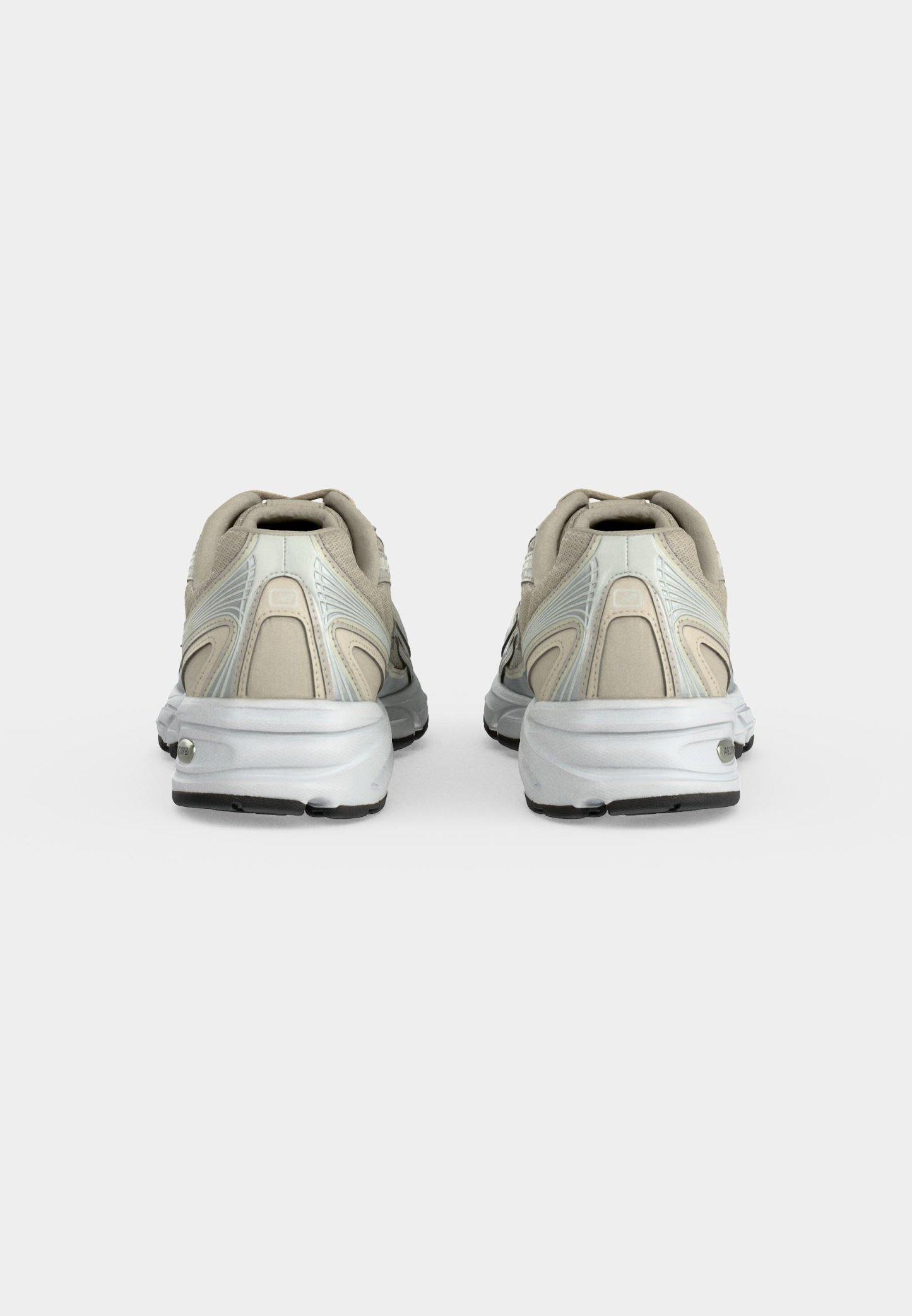Par de zapatillas deportivas beige y blancas vistas por detrás sobre un fondo liso gris claro.