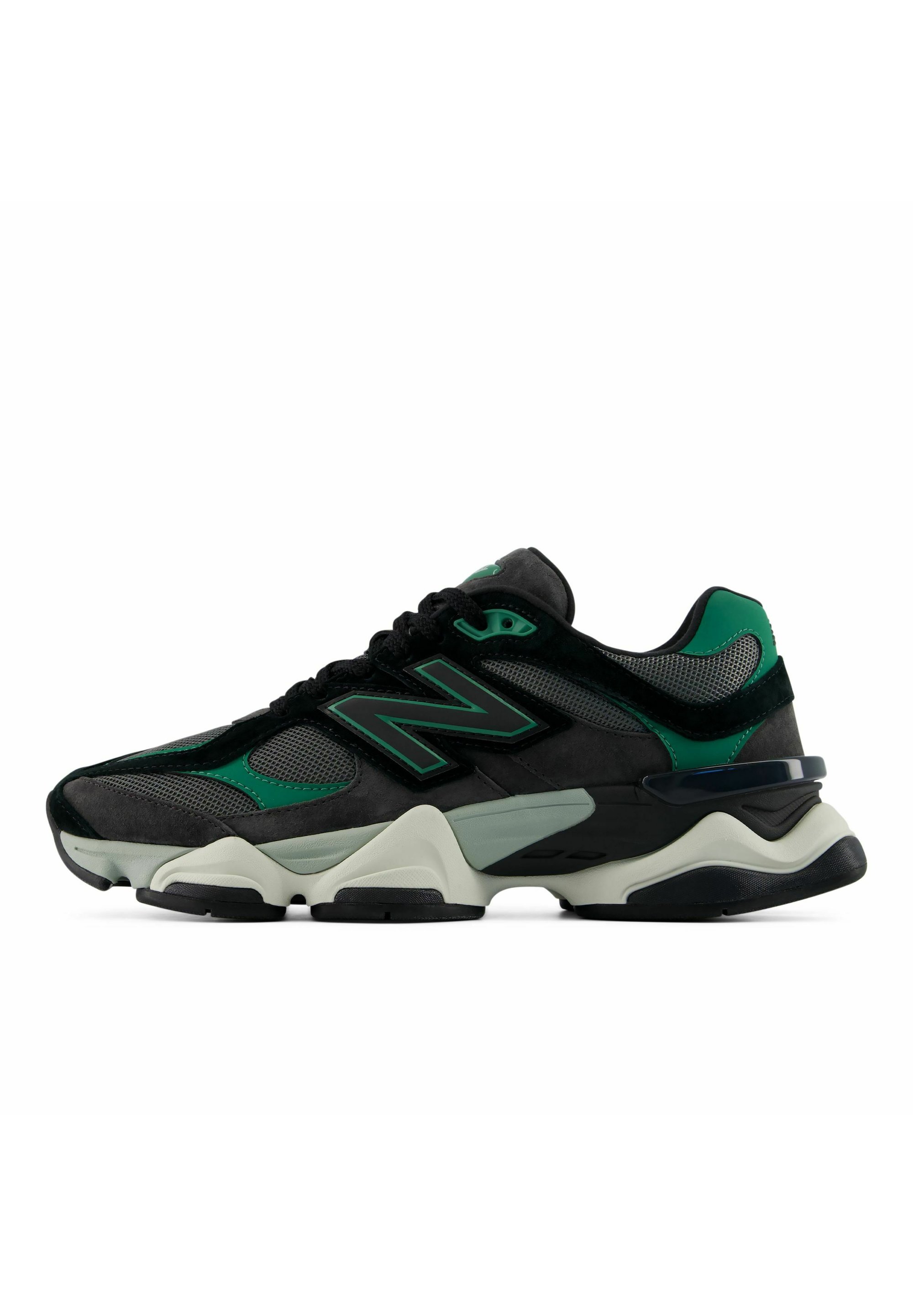 Zapatilla deportiva negra y verde con una suela gruesa blanca y negra, paneles de malla, superposiciones de ante y un gran logo "N" en el lateral.