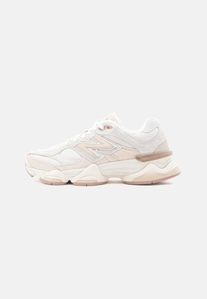 Zapatilla New Balance blanca y beige con suela gruesa, diseño con cordones y paneles de tela texturizada, mostrada desde el lado exterior.