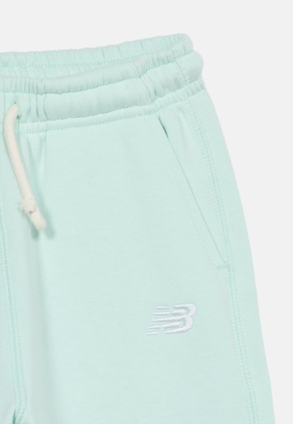 Pantalones deportivos con cintura elástica de color azul claro, cordón blanco y logo "NB" bordado en blanco cerca del bolsillo.