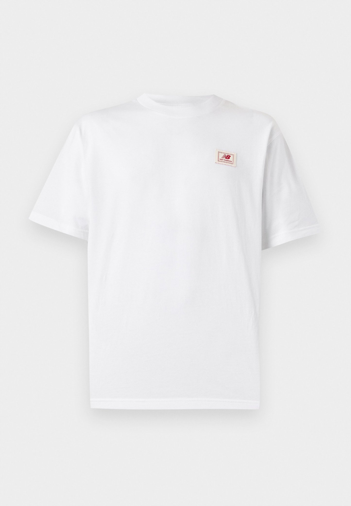 Camiseta blanca de manga corta con cuello redondo y un pequeño parche con el logo de New Balance en rojo en el pecho izquierdo.