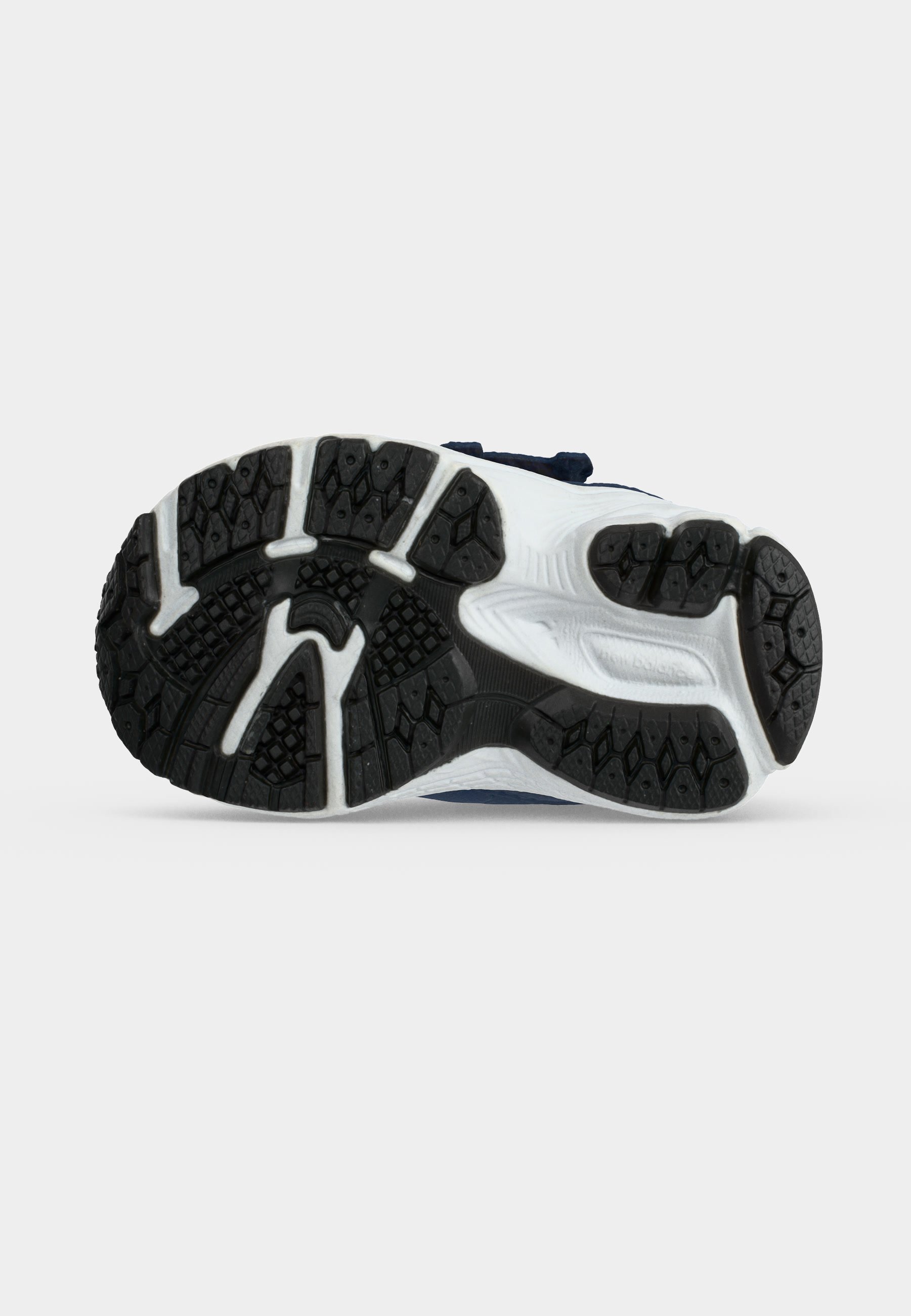 Suela de zapatilla de correr con banda de rodadura de caucho negro y entresuela blanca, mostrando patrones de agarre y textura para tracción sobre un fondo neutro.