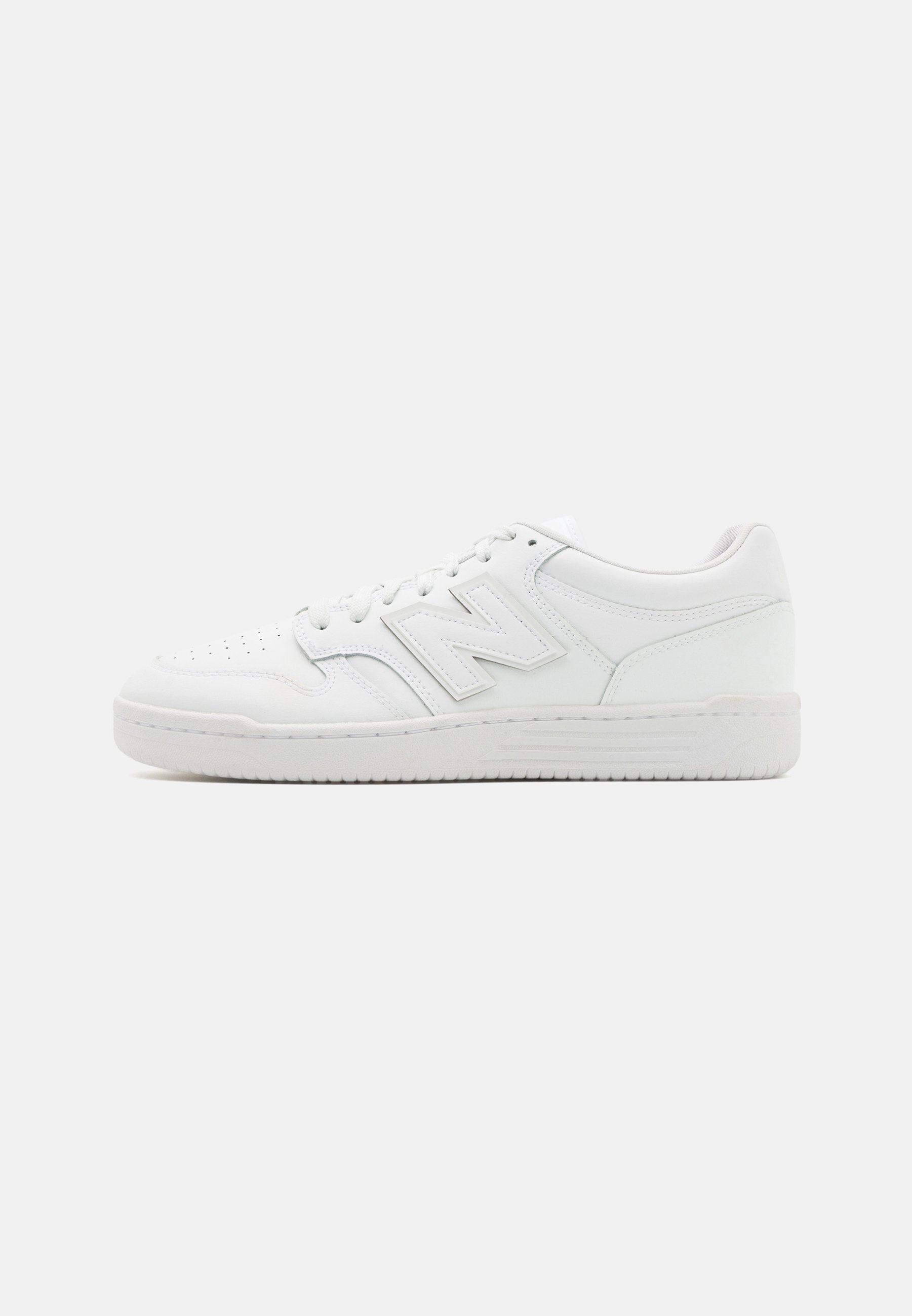 Zapatilla blanca hecha de cuero suave, con puntera perforada, suela de goma texturizada, cordones planos y un prominente logo 'N' en el lateral.