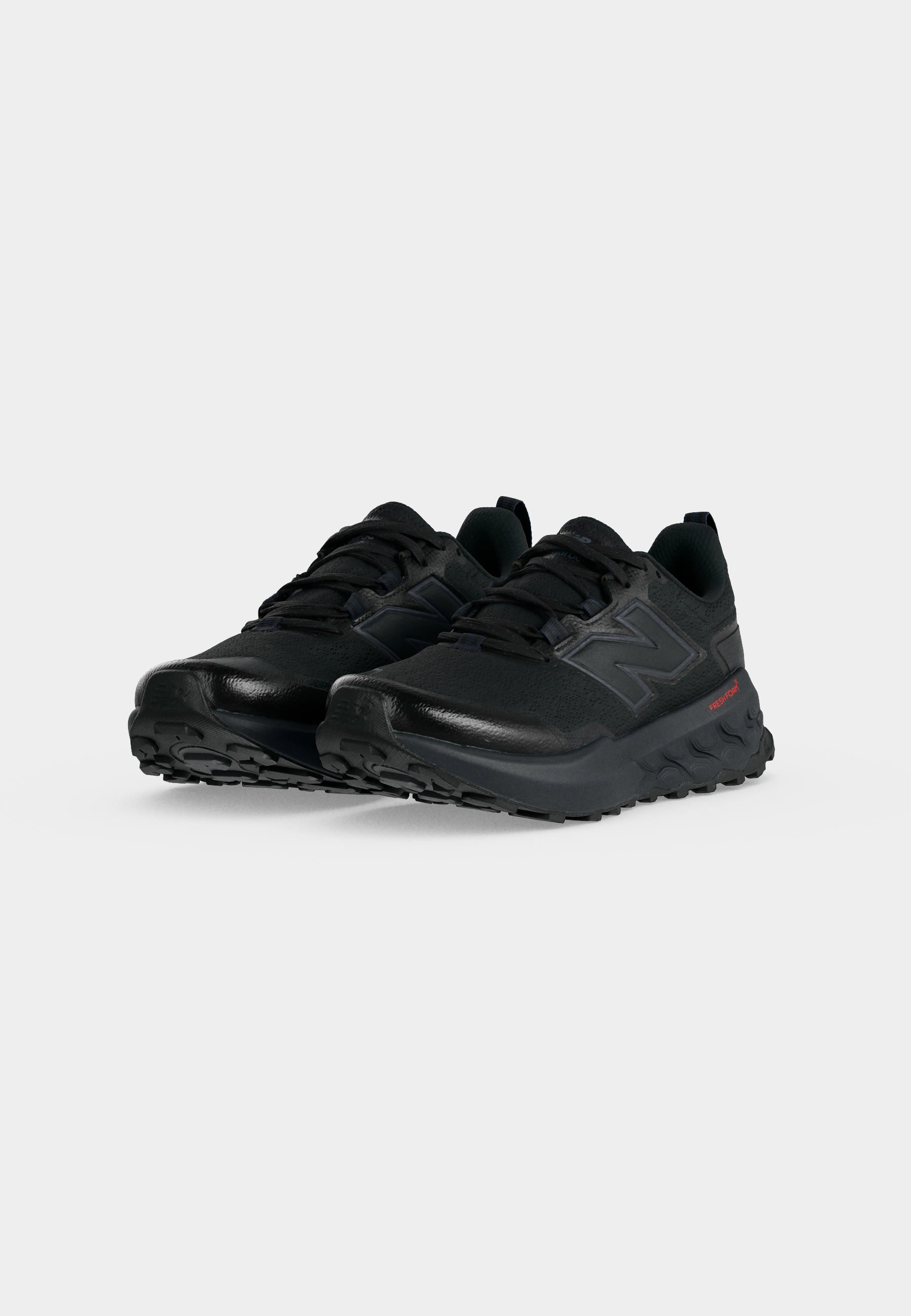 Par de zapatillas deportivas negras con suelas texturizadas y cordones, con un logo en el lateral, mostradas sobre un fondo blanco liso.