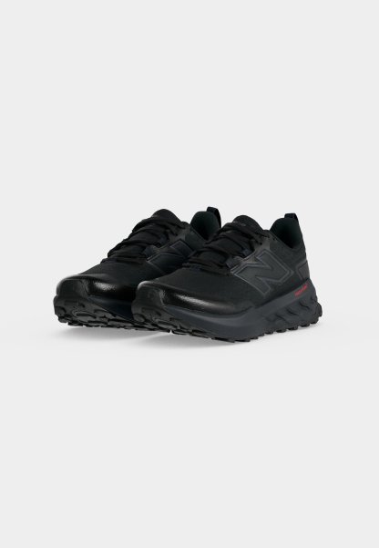 Par de zapatillas deportivas negras con suelas texturizadas y cordones, con un logo en el lateral, mostradas sobre un fondo blanco liso.