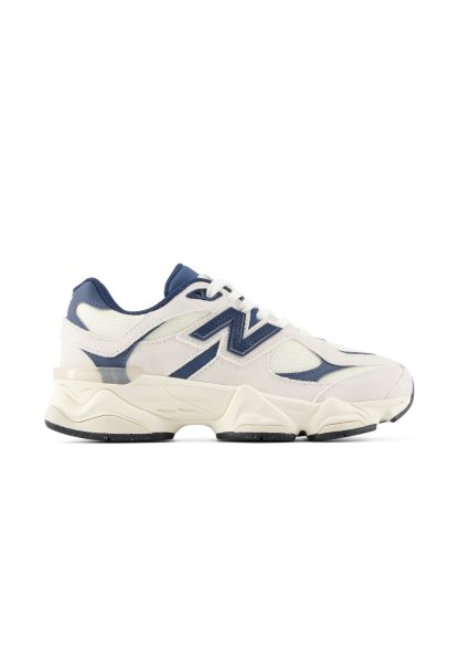 Zapatilla deportiva blanca y azul marino con detalles de malla y cuero, suela gruesa y logotipo en el lateral, vista desde el lado exterior.