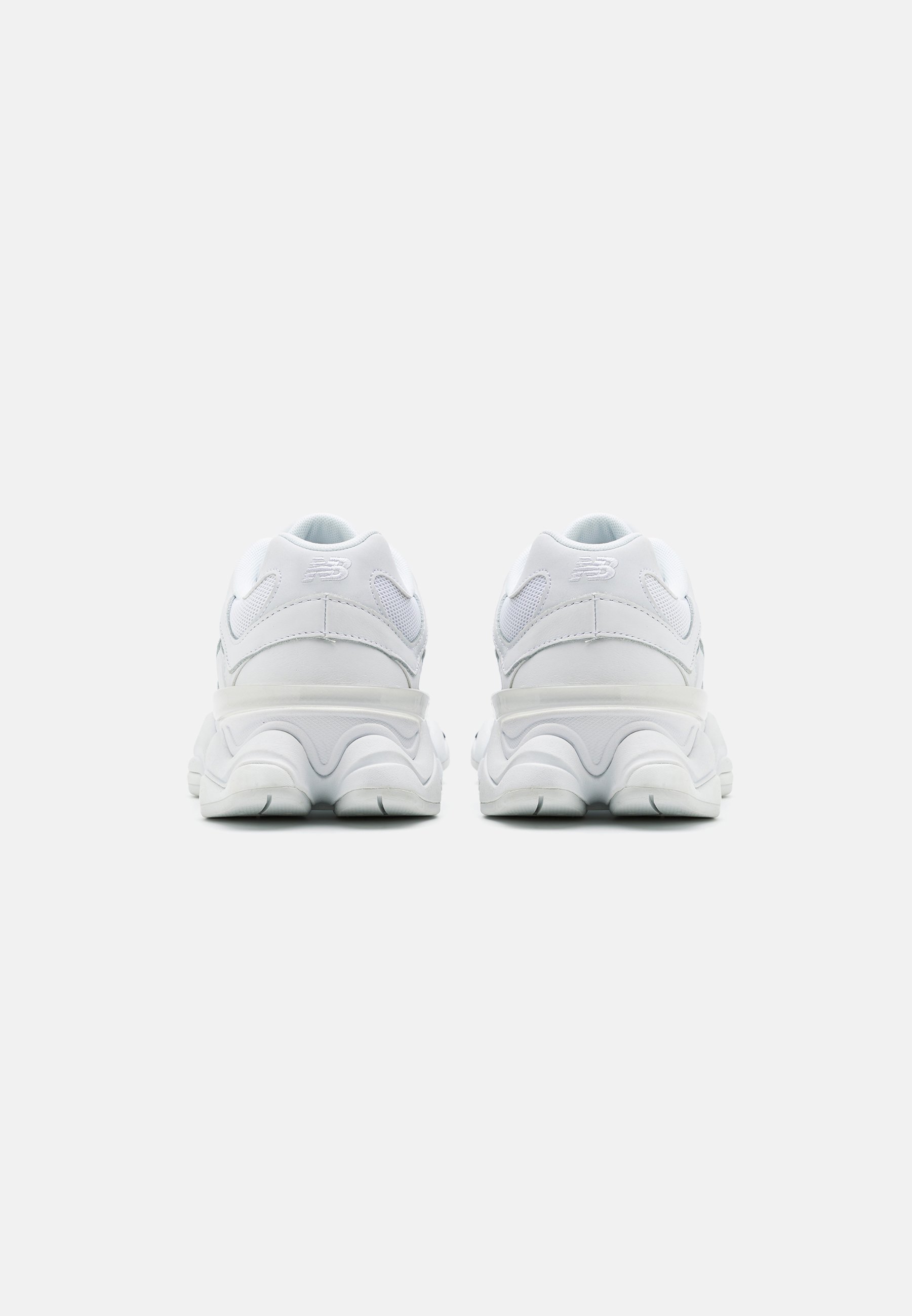 Zapatillas deportivas blancas con un talón redondeado y acolchado. Materiales de malla y sintéticos con acentos texturizados. Diseño de suela voluminoso para mayor estabilidad.