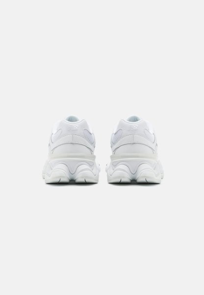 Zapatillas deportivas blancas con un talón redondeado y acolchado. Materiales de malla y sintéticos con acentos texturizados. Diseño de suela voluminoso para mayor estabilidad.