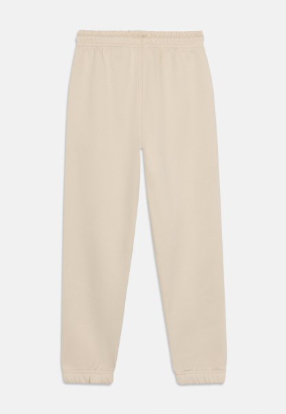 Pantalones deportivos casuales beige con cintura elástica y puños ajustados, presentados planos sobre un fondo blanco.