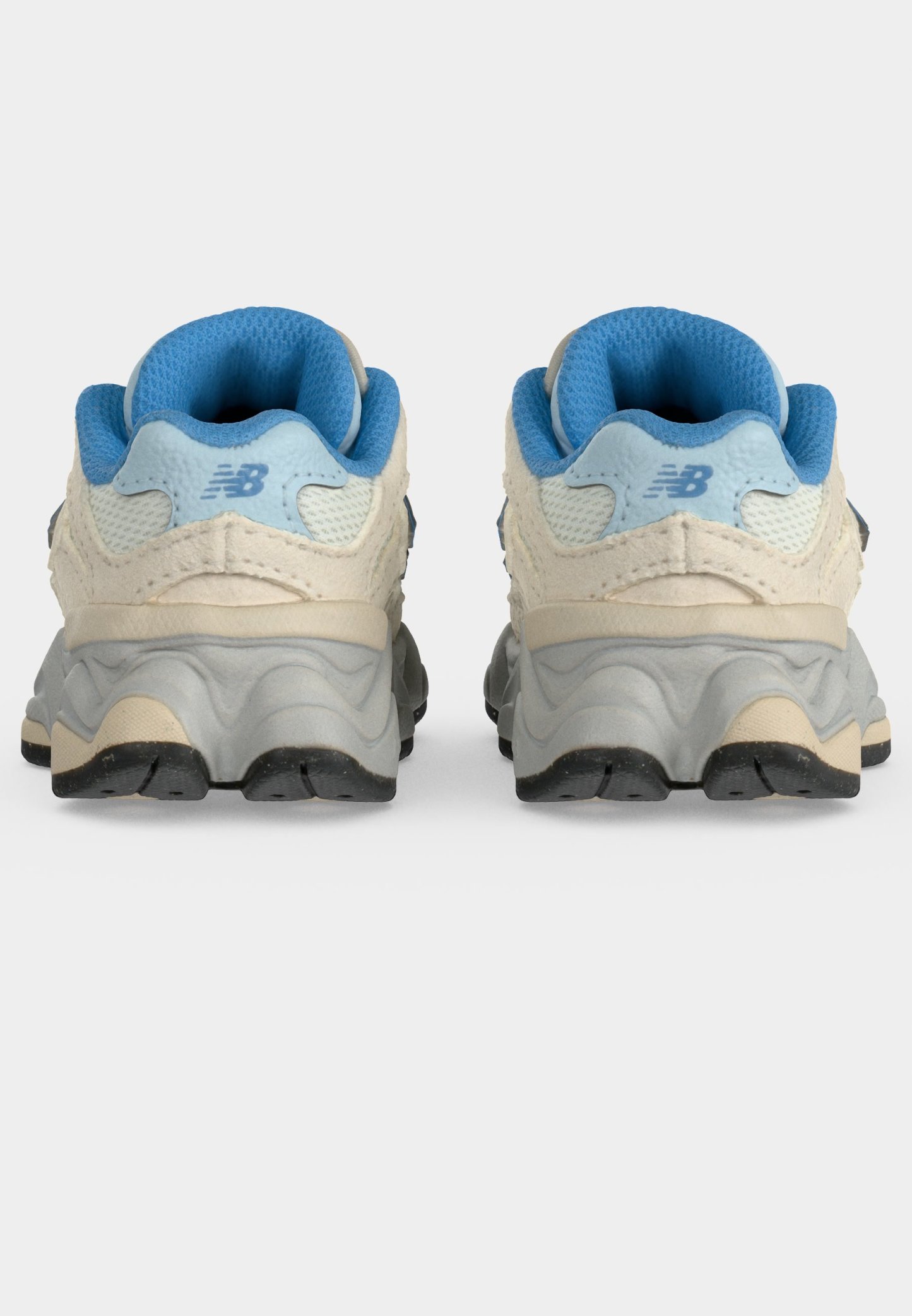 Par de zapatillas deportivas blancas y azul claro vistas desde atrás, mostrando interiores acolchados azules y suelas gruesas texturizadas de color gris.