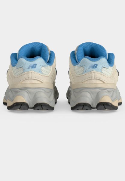 Par de zapatillas deportivas blancas y azul claro vistas desde atrás, mostrando interiores acolchados azules y suelas gruesas texturizadas de color gris.