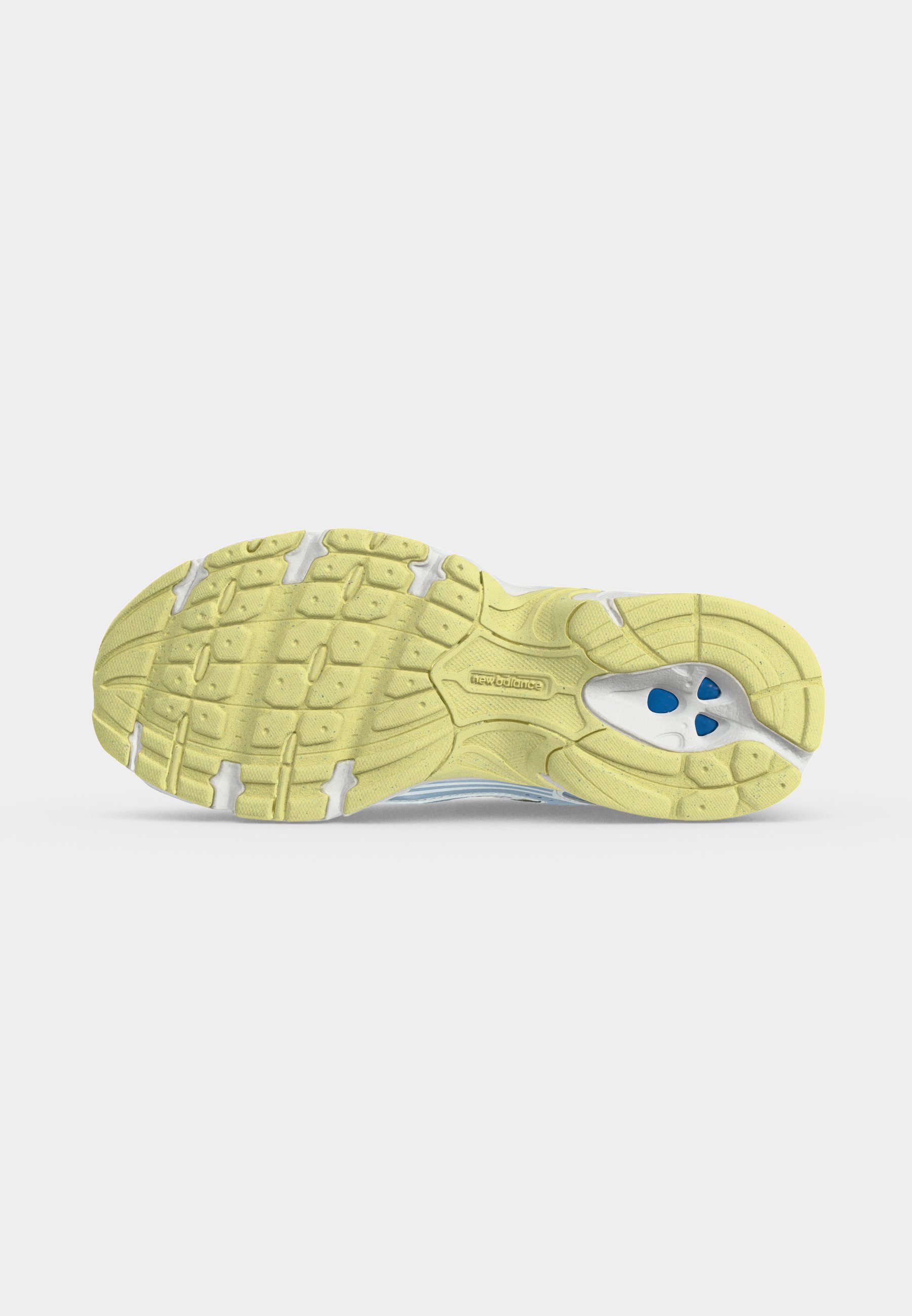 Suela de una zapatilla de running New Balance amarilla con agarre texturizado y amortiguación azul visible en el área del talón sobre un fondo blanco liso.