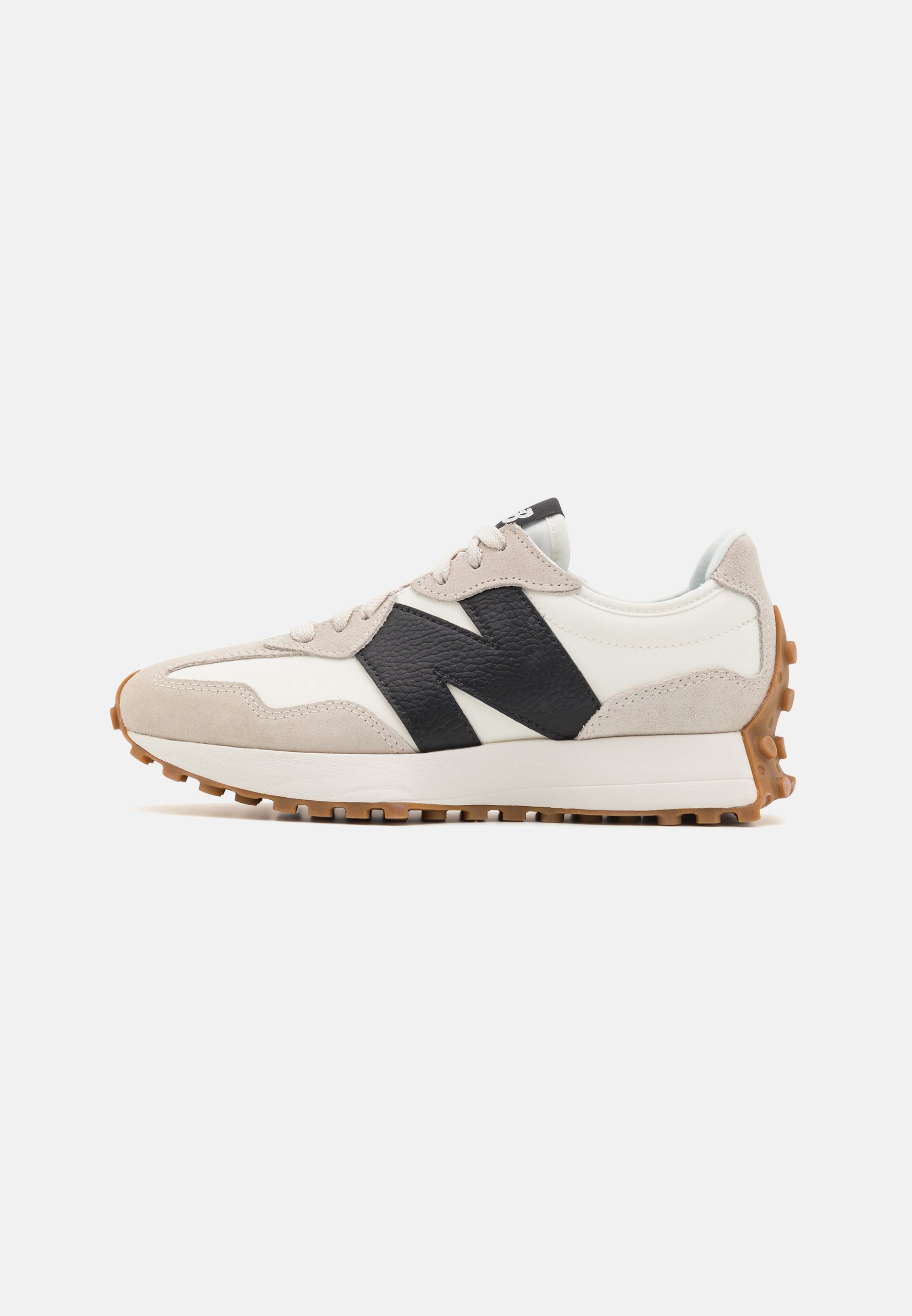 Zapatilla blanca y beige con logo negro "N", suela de goma con tacos de tracción y diseño con cordones mostrada en perfil lateral.