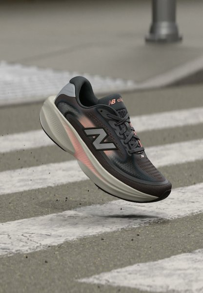 Zapatilla de running New Balance negra y gris con detalles en rosa flotando sobre una calle gris con líneas blancas de paso de peatones.