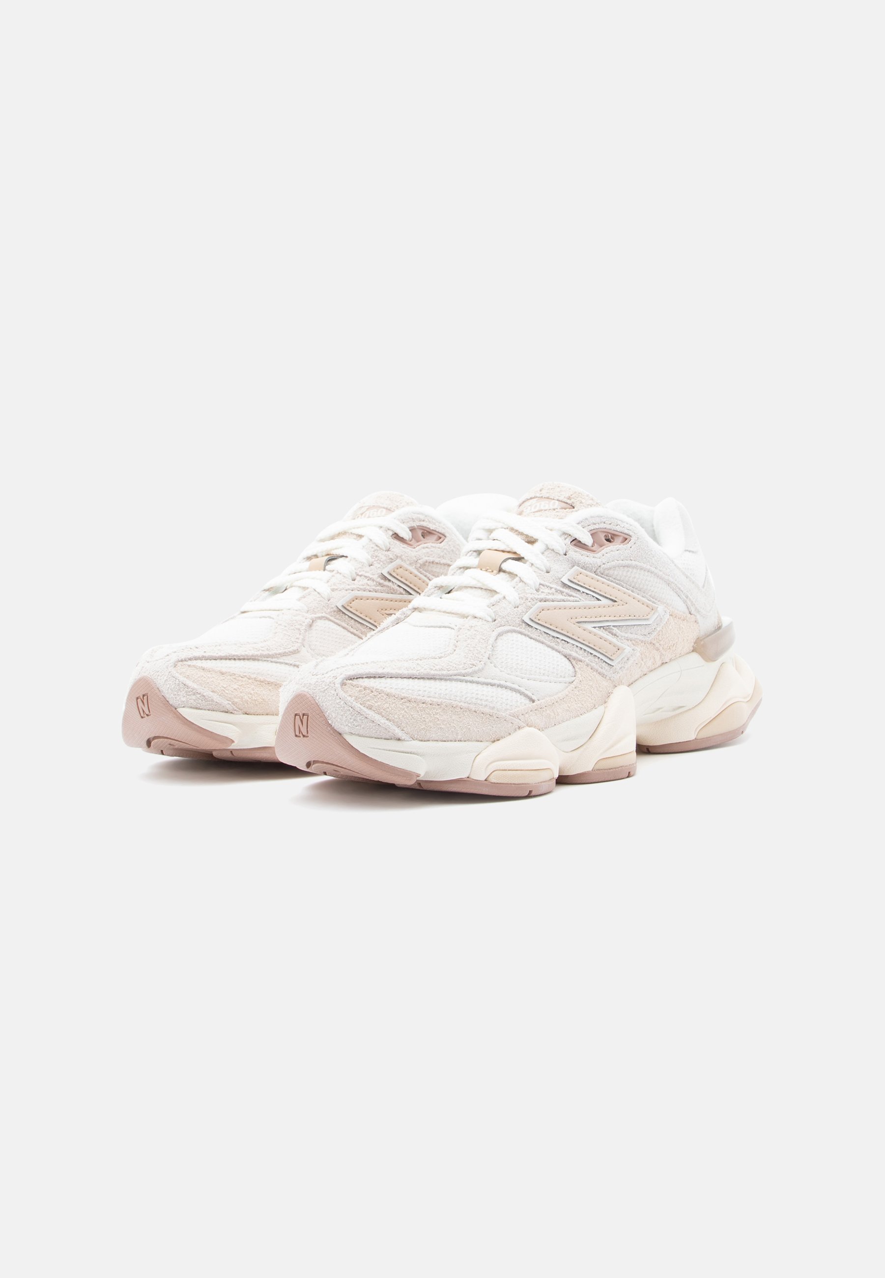 Par de zapatillas New Balance blancas y beige con suelas gruesas, cordones atados, mostradas en un ligero ángulo sobre fondo blanco.