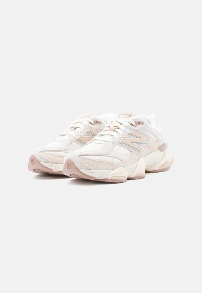 Par de zapatillas New Balance blancas y beige con suelas gruesas, cordones atados, mostradas en un ligero ángulo sobre fondo blanco.