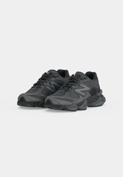 Par de zapatillas deportivas negras y gris oscuro con suelas gruesas y diseño con cordones sobre un fondo claro y liso.