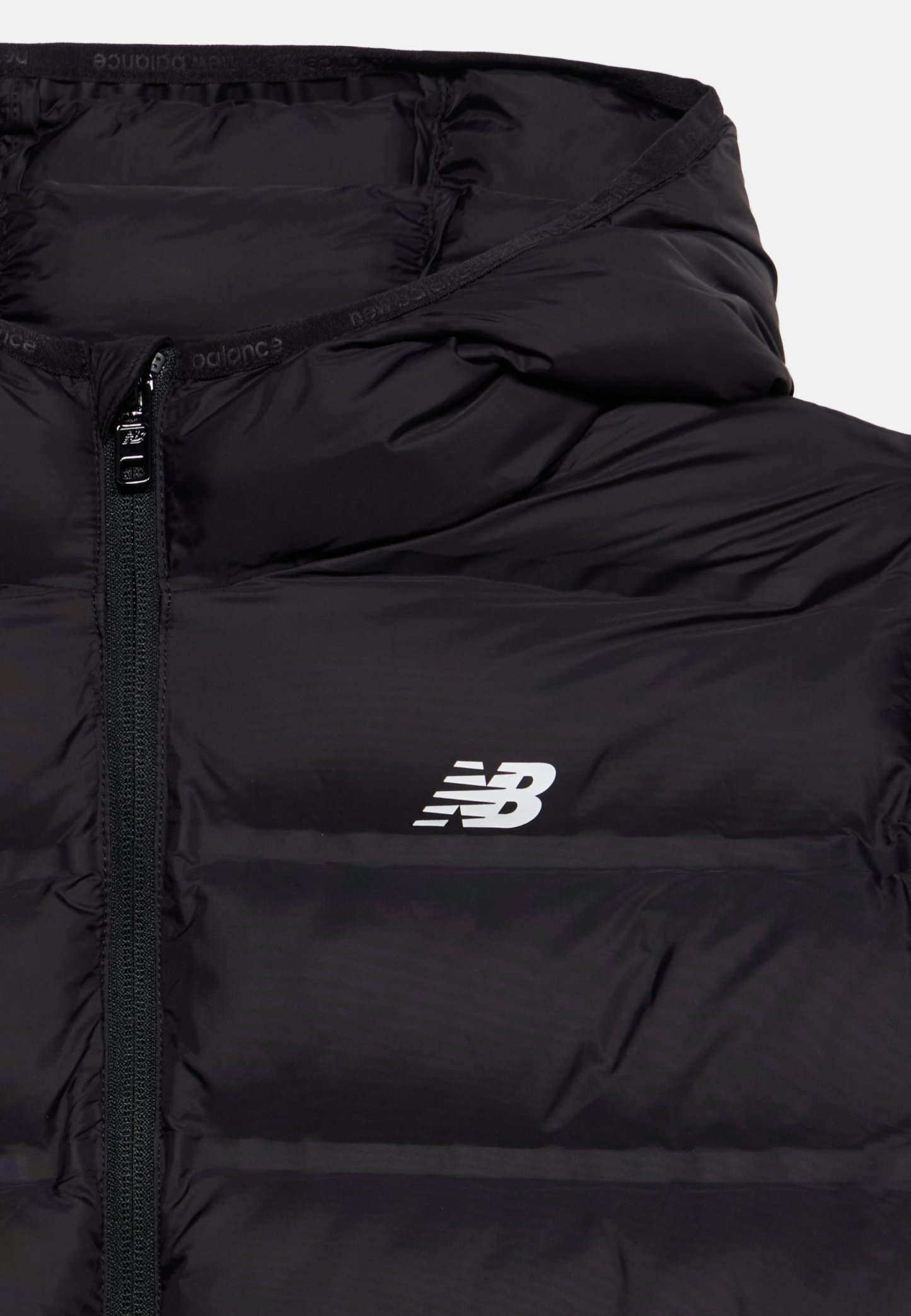 Chaqueta acolchada negra con cremallera frontal y capucha, con un logotipo blanco de New Balance en el pecho izquierdo.