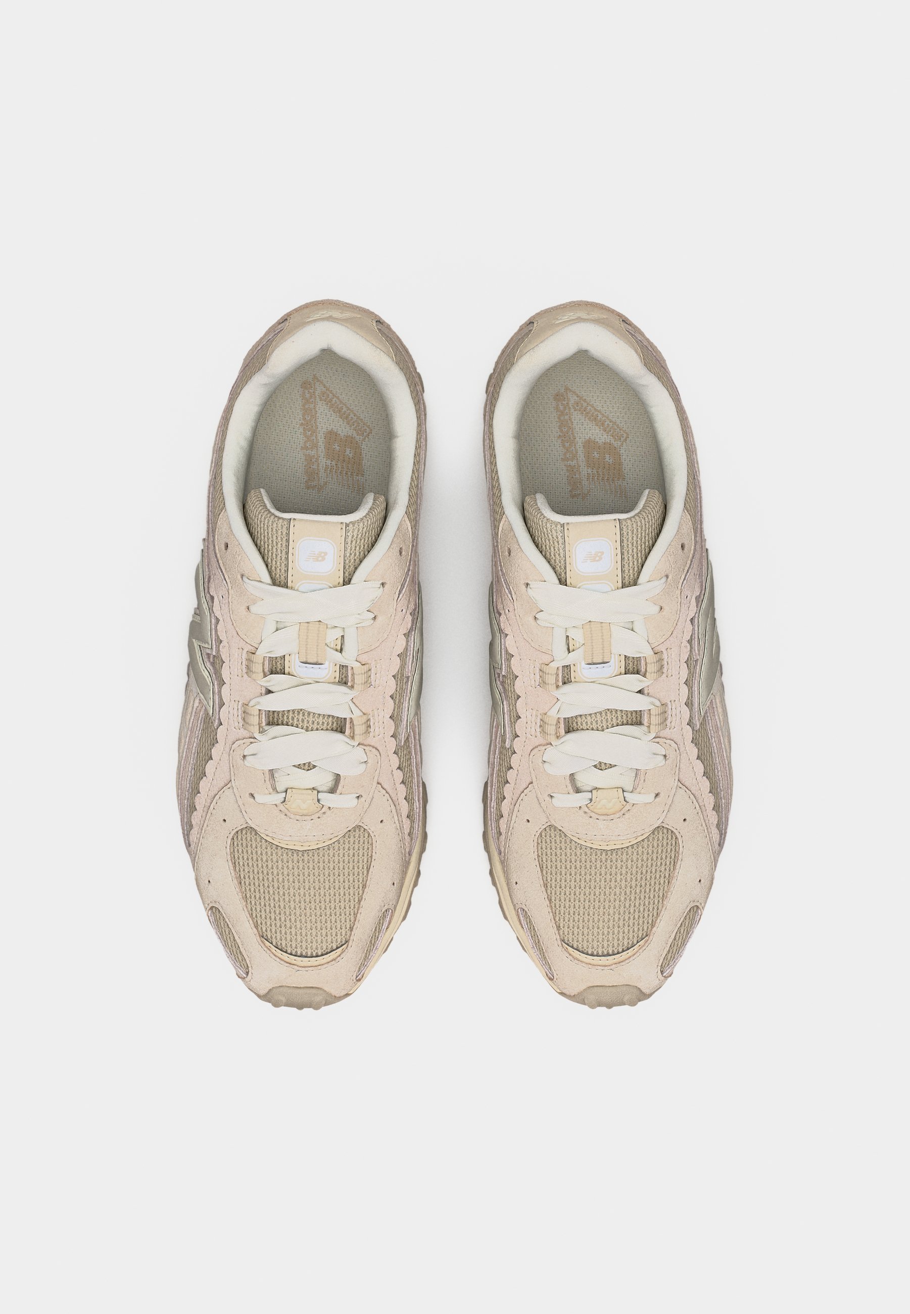 Par de zapatillas New Balance beige y crema con cordones, vista desde arriba sobre un fondo blanco.