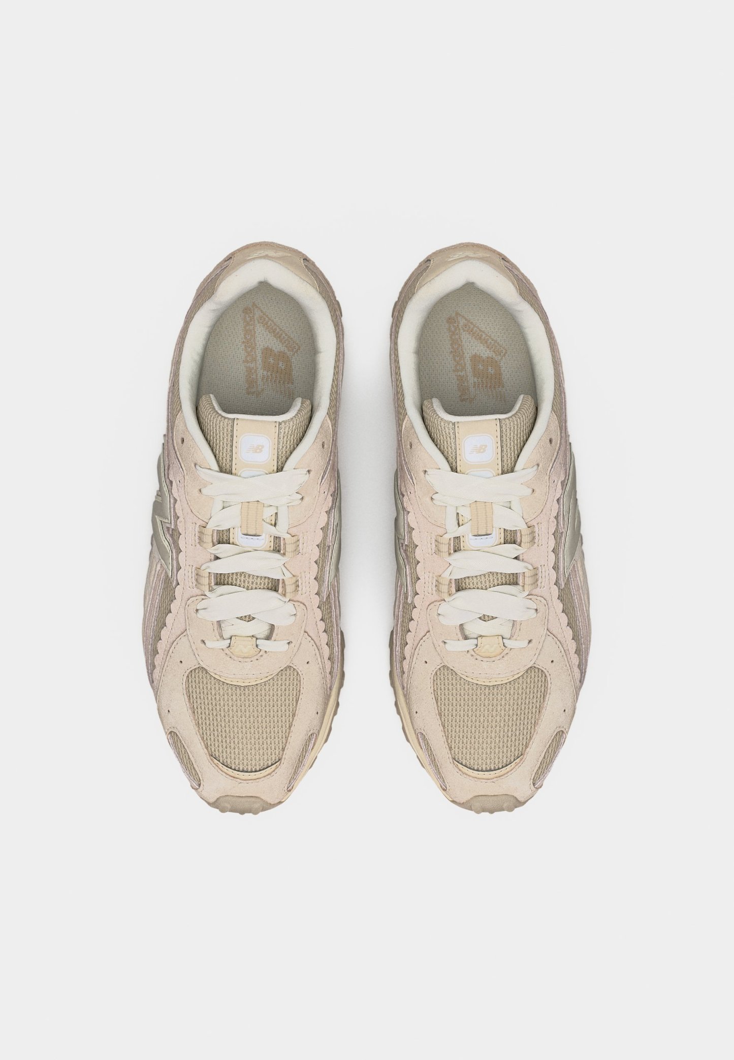 Par de zapatillas New Balance beige y crema con cordones, vista desde arriba sobre un fondo blanco.