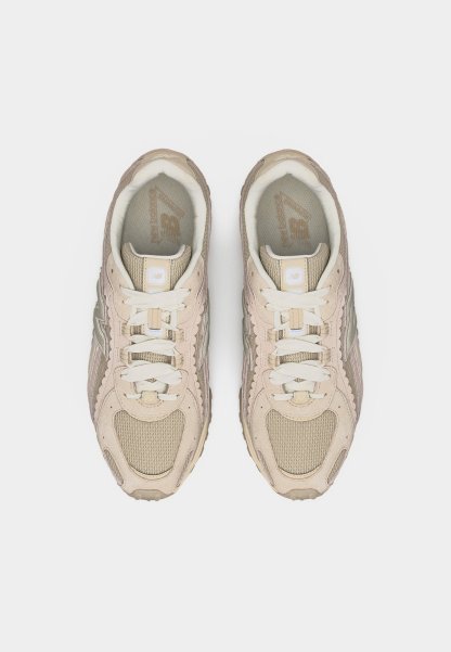Par de zapatillas New Balance beige y crema con cordones, vista desde arriba sobre un fondo blanco.