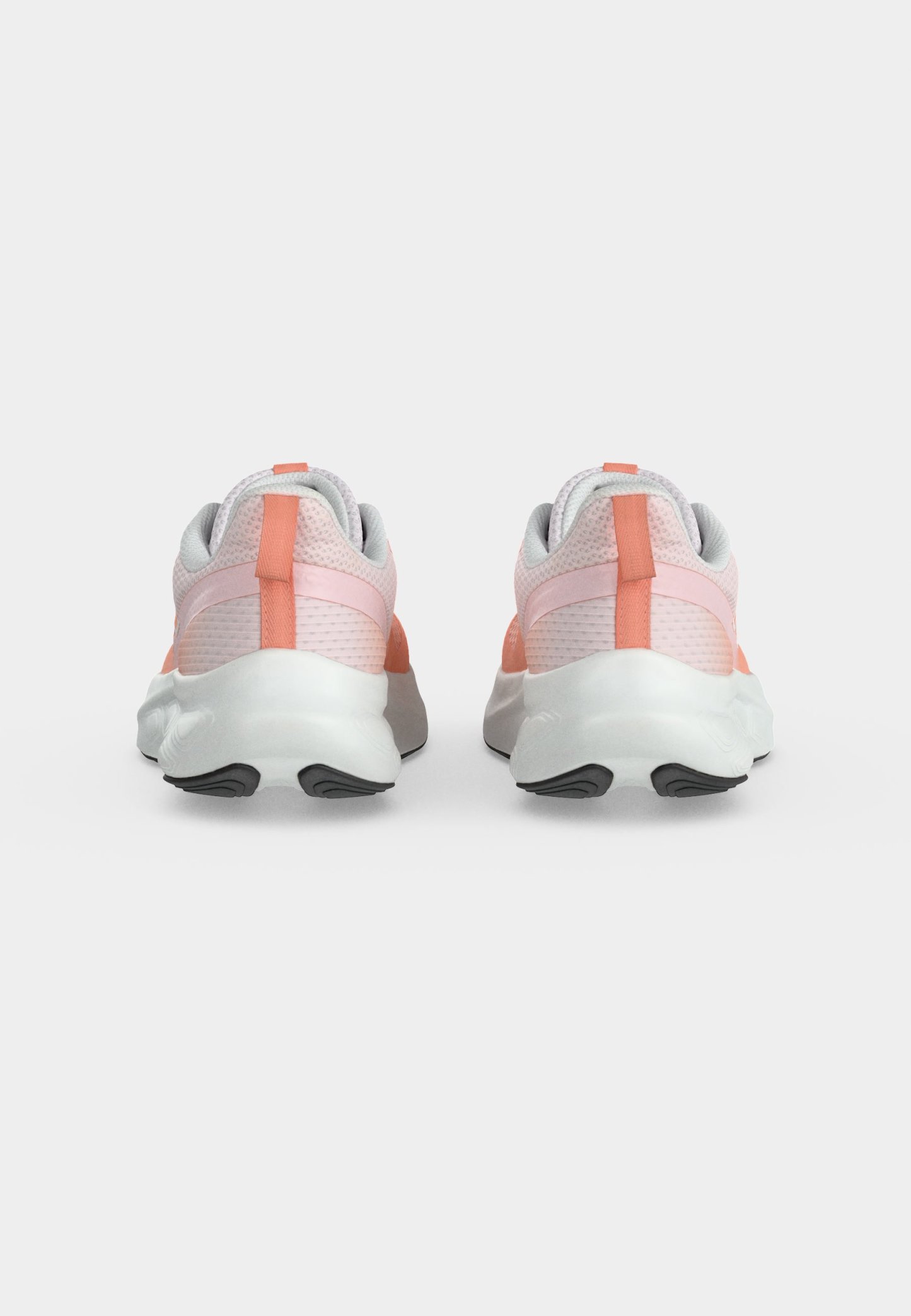 Par de zapatos deportivos de color rosa claro y coral con suelas blancas mostrados desde atrás sobre un fondo blanco liso.