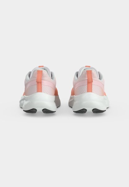 Par de zapatos deportivos de color rosa claro y coral con suelas blancas mostrados desde atrás sobre un fondo blanco liso.