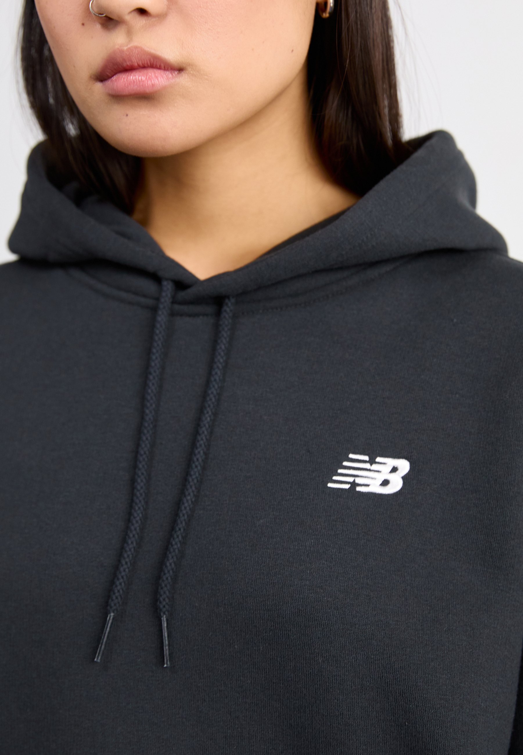 Sudadera con capucha de color gris oscuro, confeccionada en tejido suave, que cuenta con un bolsillo frontal, cordones en la capucha y un logo bordado en blanco en el pecho.
