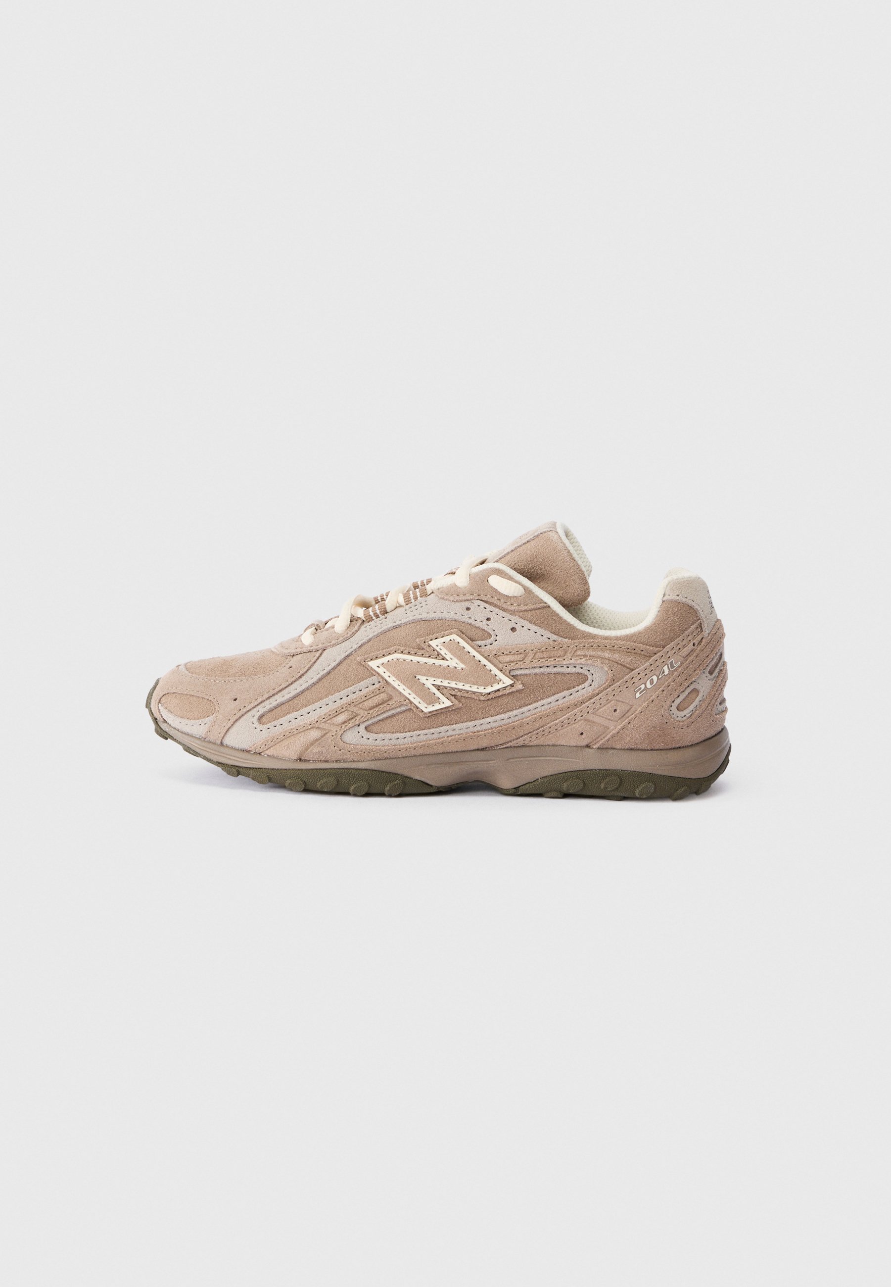 Zapatilla New Balance 2040 beige con parte superior de gamuza, cordones crema y suela texturizada en verde oscuro, mostrada de perfil sobre fondo blanco.