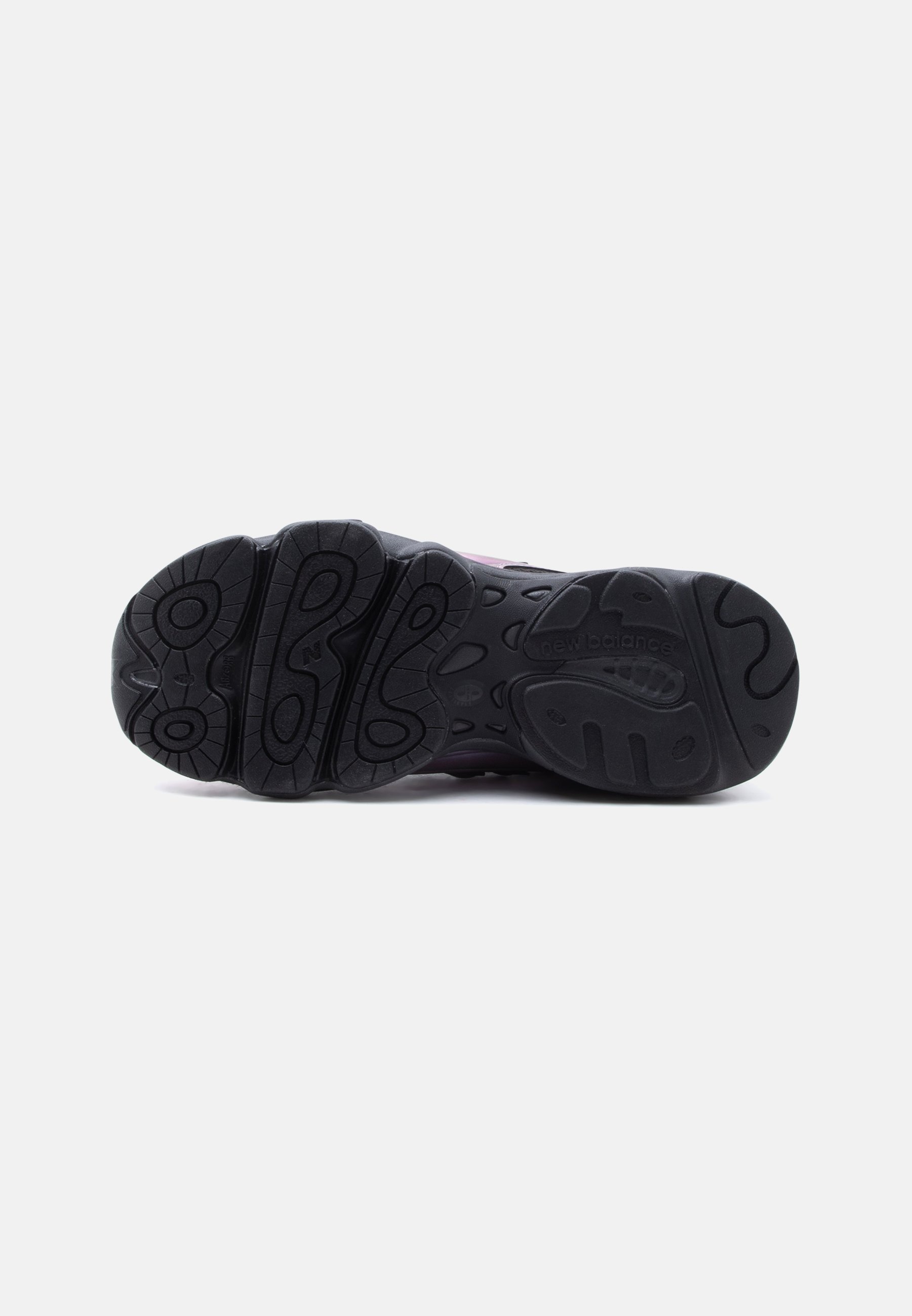 Suela de goma negra de una zapatilla New Balance mostrando los patrones de la banda de rodadura y el nombre de la marca sobre un fondo blanco.