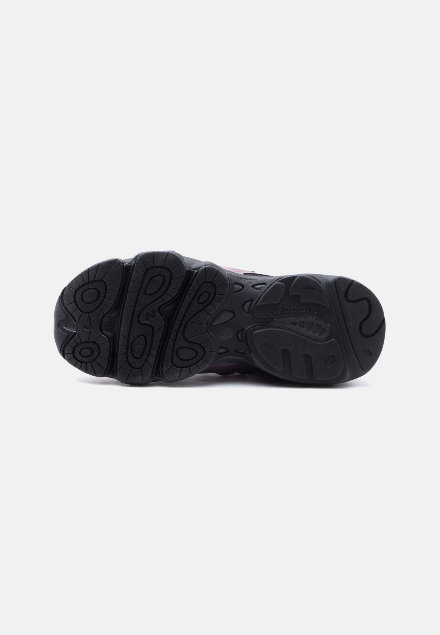 Suela de goma negra de una zapatilla New Balance mostrando los patrones de la banda de rodadura y el nombre de la marca sobre un fondo blanco.