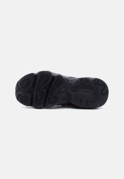 Suela de goma negra de una zapatilla New Balance mostrando los patrones de la banda de rodadura y el nombre de la marca sobre un fondo blanco.