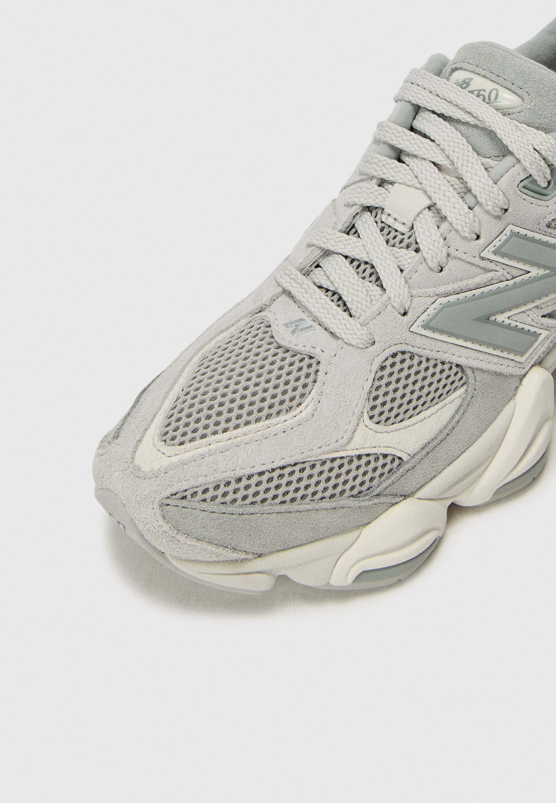 Primer plano de una zapatilla New Balance 650 de color gris claro con paneles de malla y ante y cordones gruesos y texturizados.
