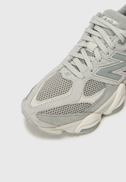 Primer plano de una zapatilla New Balance 650 de color gris claro con paneles de malla y ante y cordones gruesos y texturizados.