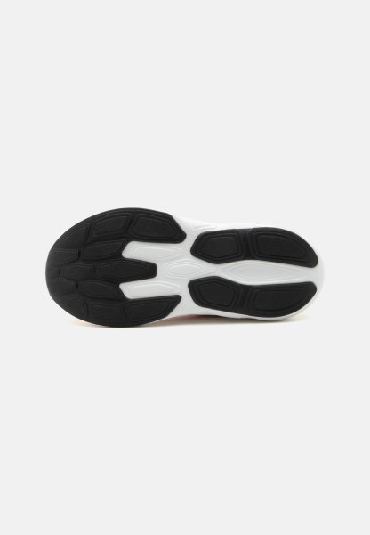 Suela de zapatilla blanca y negra con tacos de goma negra texturizados sobre un fondo blanco de entresuela.