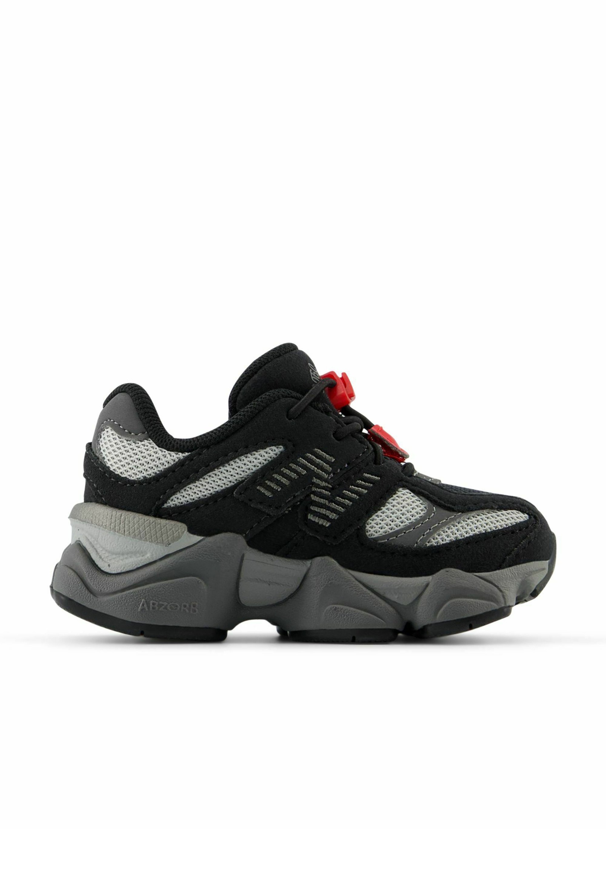 Zapatilla deportiva en negro y gris con parte superior de malla, suela de goma gruesa, acentos rojos y detalles geométricos en los laterales.