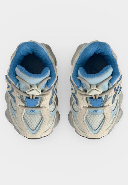 Par de zapatillas deportivas azul claro y gris con cuello acolchado y cordones elásticos vistas desde arriba sobre un fondo blanco.