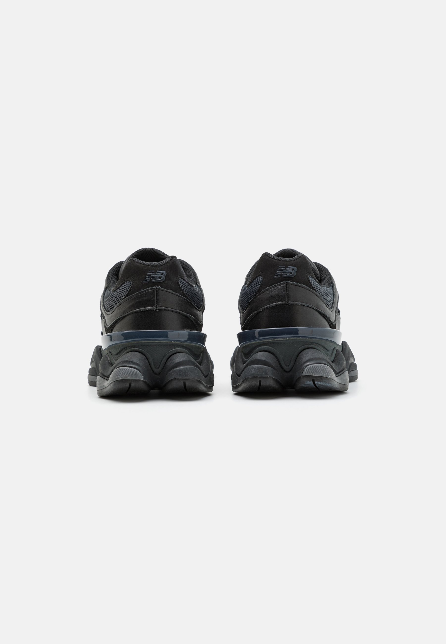 Zapatillas deportivas negras con un acabado texturizado, que cuentan con una suela acolchada, detalles de malla y un prominente talón de goma.