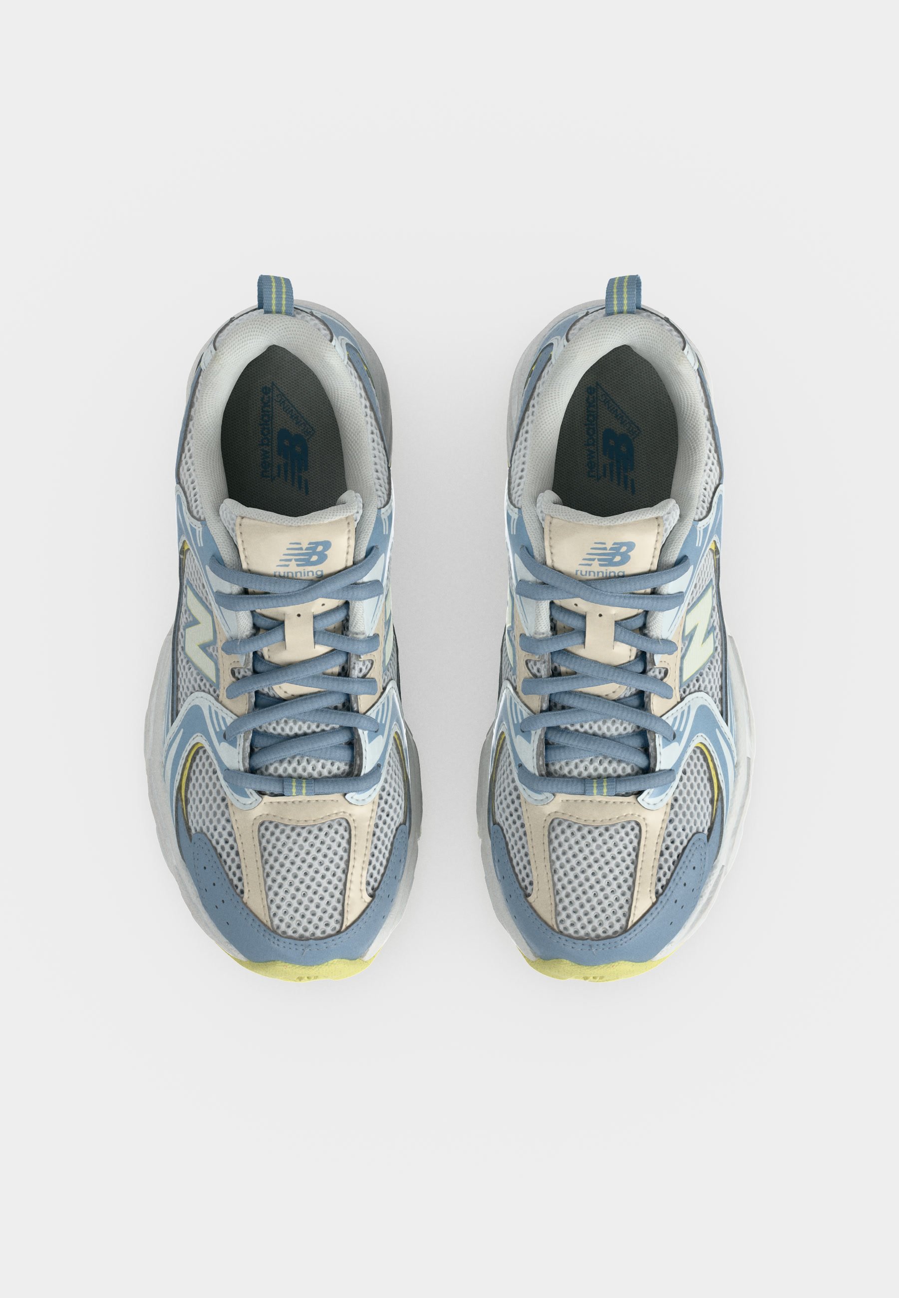 Par de zapatillas de running New Balance azules, grises y blancas vistas desde arriba, con detalles de malla y cuero y cordones azules.