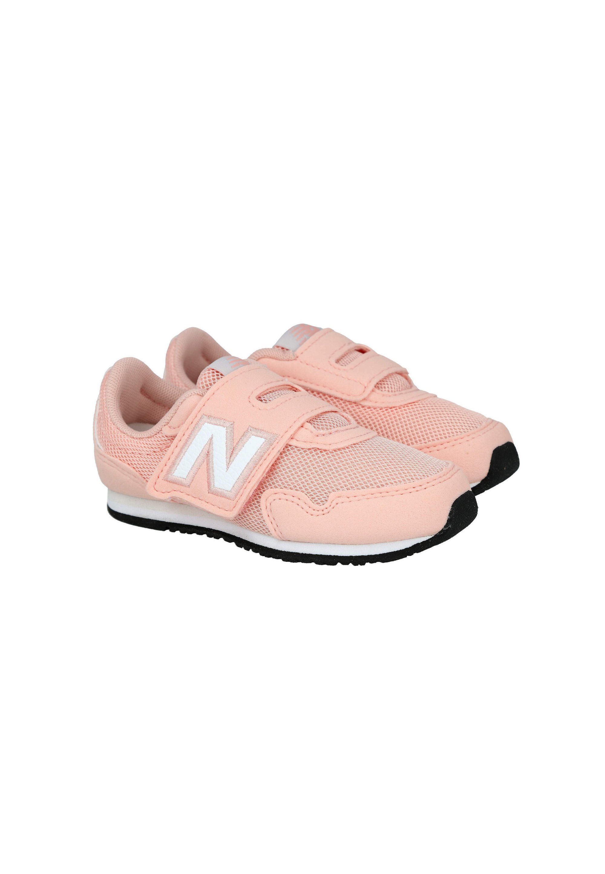 Par de zapatillas infantiles de color rosa claro con logo blanco "N", tiras de velcro y puntas de suela negras, mostradas sobre un fondo blanco.
