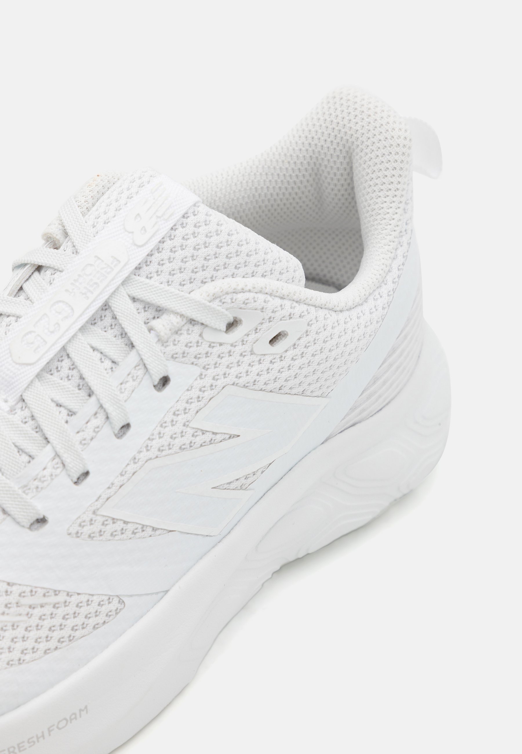 Zapatilla deportiva blanca hecha de tela de malla con una superficie texturizada, cuenta con cordones, un collar acolchado y una suela gruesa y acolchada.