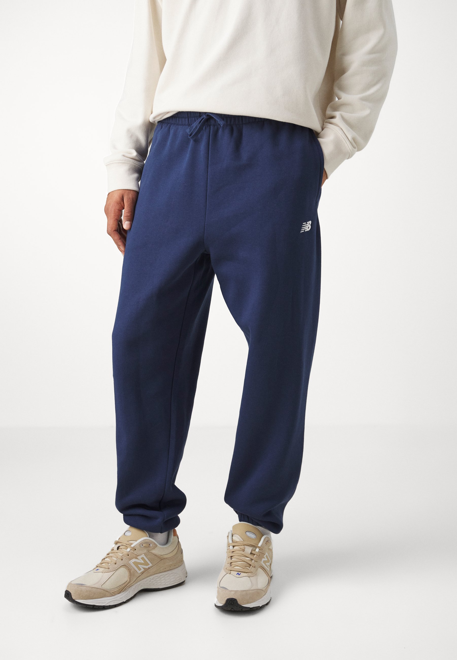 Pantalones de chándal azul marino con cintura elástica, cordón y bolsillos laterales; presenta un pequeño logo blanco en el muslo izquierdo.
