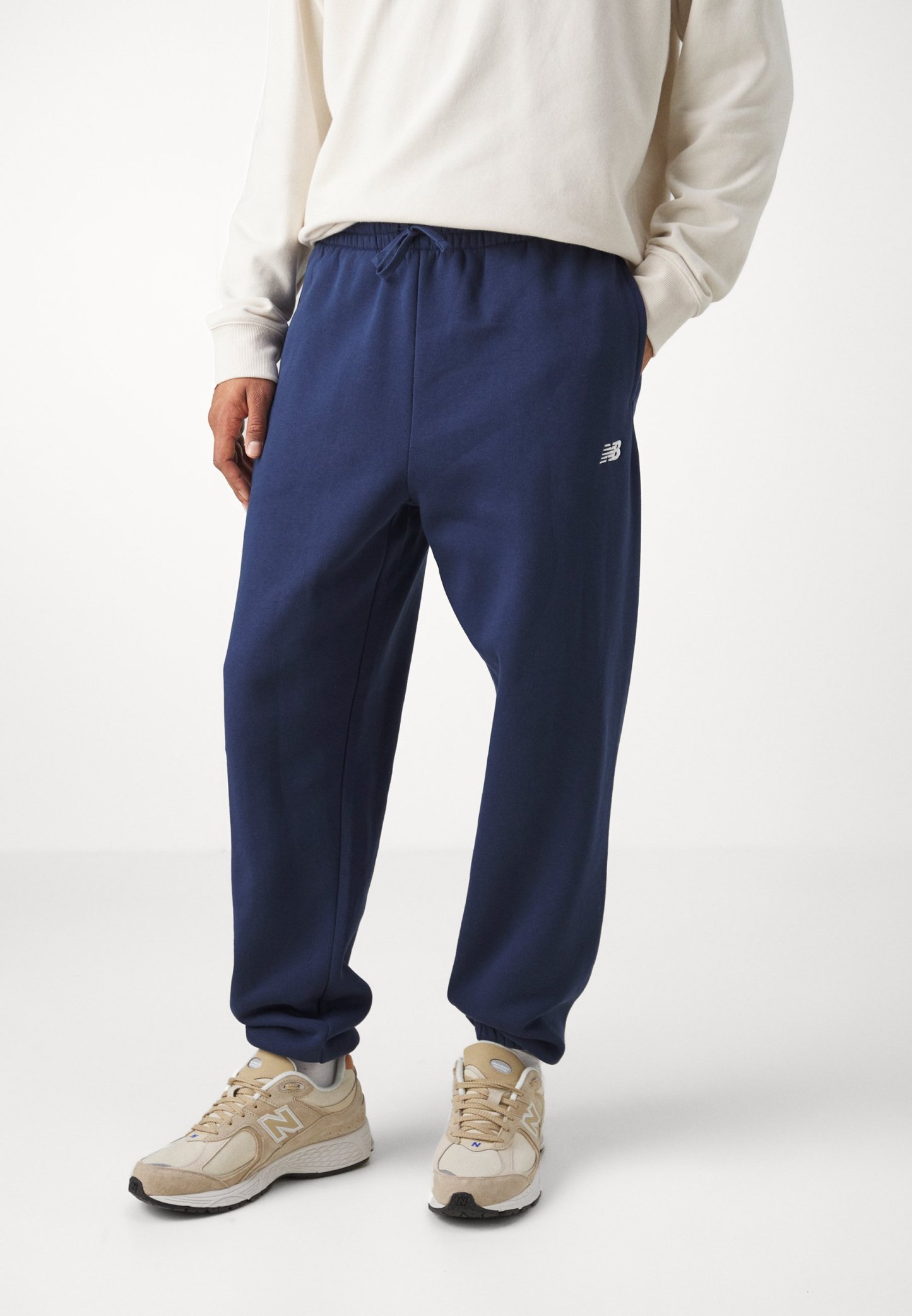 Pantalones de chándal azul marino con cintura elástica, cordón y bolsillos laterales; presenta un pequeño logo blanco en el muslo izquierdo.